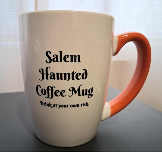 "Salem Haunted Coffee Mug" "Drink at Your Own Risk" White, ceramic, 12oz, coffee mug with orange handle and interior.